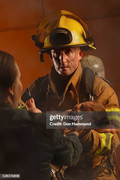 fire fighter passing baby to mother - food safety audit stock pictures, royalty-free photos & images