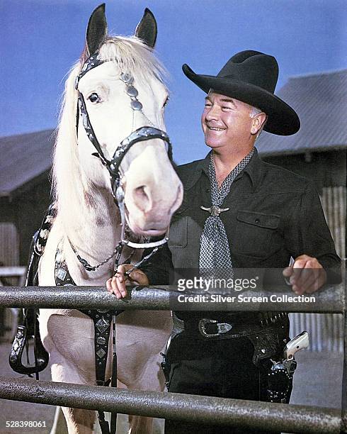 American actor William Boyd standing beside a horse and wearing a western outfit, circa 1960. He is best known for the 'Hopalong Cassidy' series of...