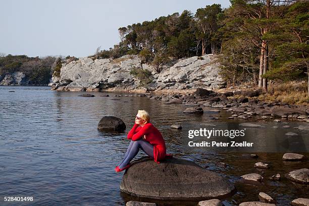 a young woman sits on a large rock on muckross lake; killarney county kerry ireland - killarney lake stock pictures, royalty-free photos & images