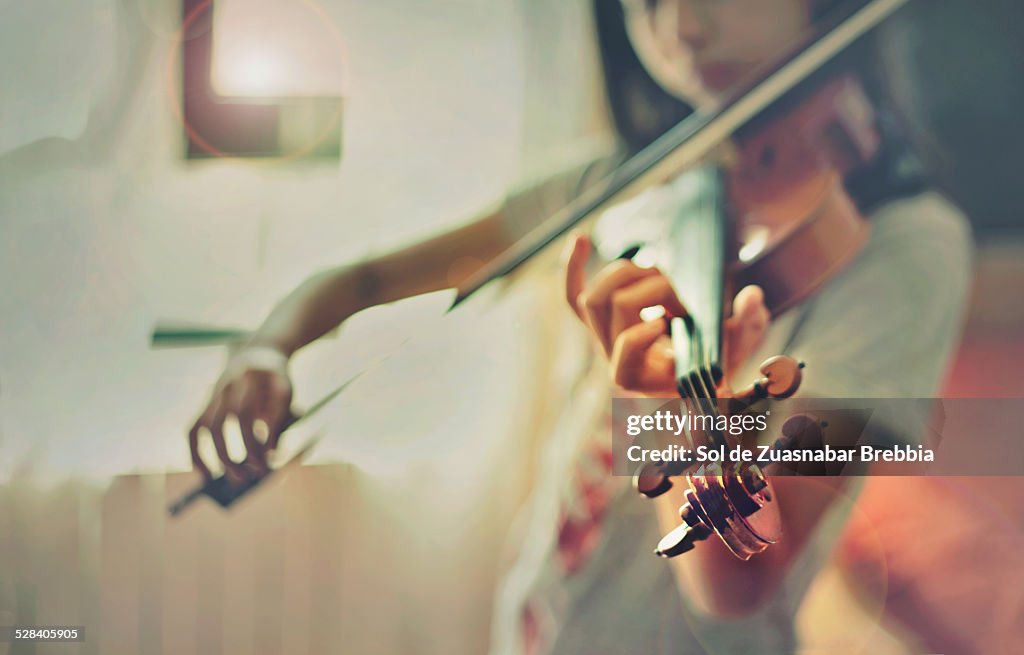 Girl playing a violin in front of a window