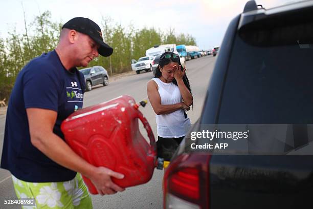 Marilou Wood fights back tears as husband Jim Wood fills up his car with gas after fleeing forest fires in Fort McMurray on May 4, 2016 Numerous...