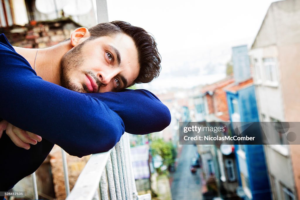 Handsome turkish man day dreaming on his Istanbul balcony