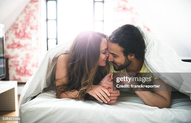 couple kissing on the bed on early morning - man and woman cuddling in bed stockfoto's en -beelden