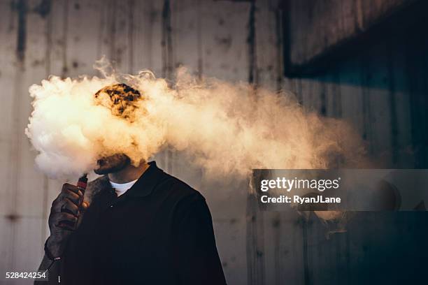 hombre usando un cigarrillo eléctrico - humo de cigarrillo electrónico fotografías e imágenes de stock