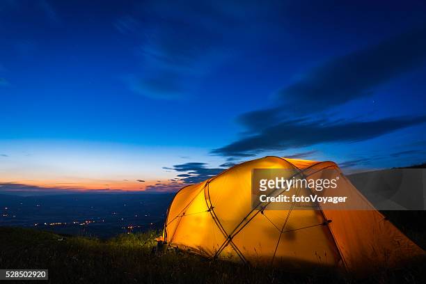 yellow mountain tent illuminated at dusk on summer mountain ridge - base camp stock pictures, royalty-free photos & images