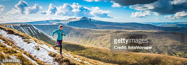 Teenager trail running along mountain path Brecon Beacons panorama Wales