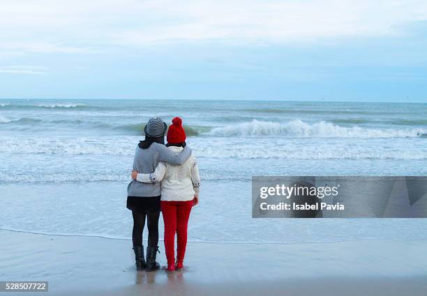 mother with daughter standing on beach - monoparental stock-fotos und bilder