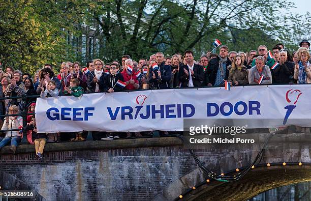 People stand on a bridge which displays a banner reading 'Pass On Freedom' watch the Liberation Day Concert on May 5, 2016 in Amsterdam, Netherlands....