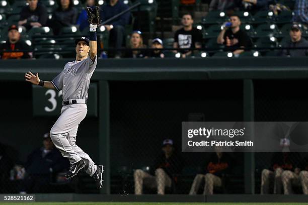 Dustin Ackley of the New York Yankees makes a catch on Manny Machado of the Baltimore Orioles in the third inning at Oriole Park at Camden Yards on...