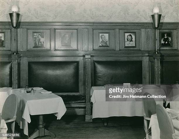 Photograph of Jack Dempsey's Bar featuring unoccupied booths with cloth covered tables, wood paneling and photos on walls.