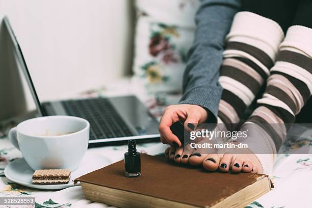 girl applying nailpolish at toenails - girls in socks stockfoto's en -beelden