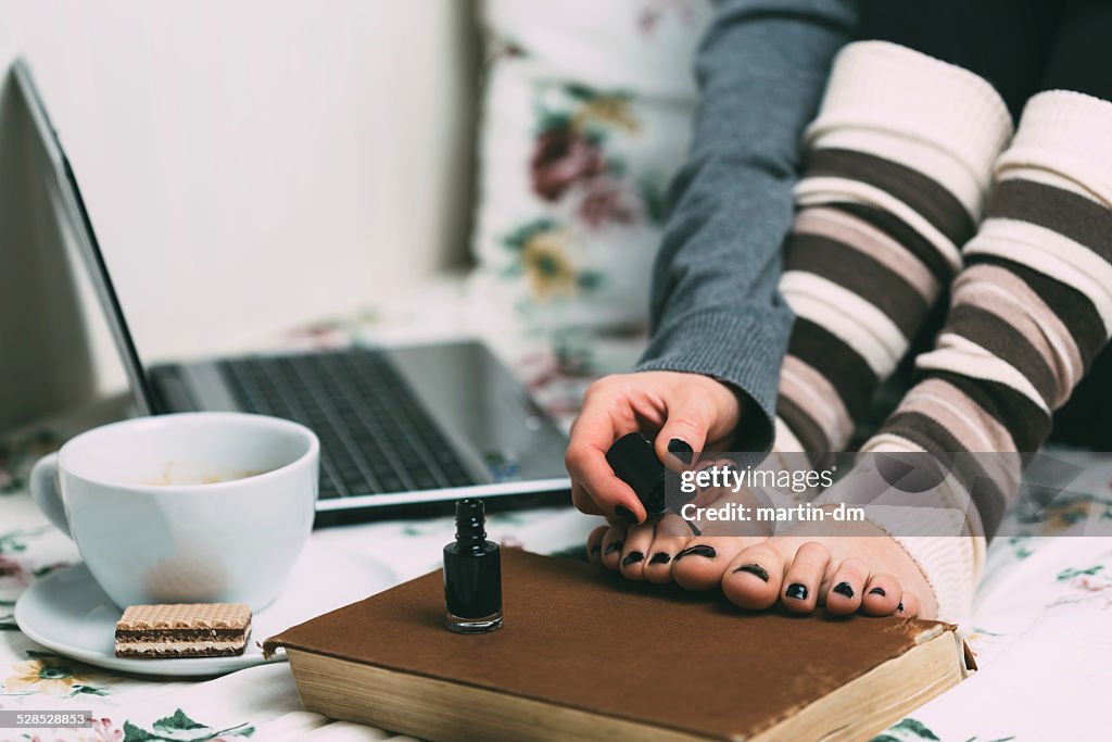 Menina aplicando nailpolish com as unhas dos pés