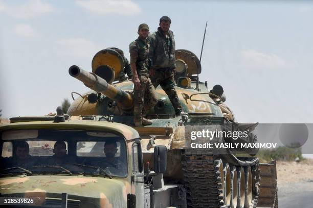 Syrian soldiers stand on a tank loaded on a lorry as they patrol their positions near the ancient city of Palmyra on May 5, 2016. Leading Russian...