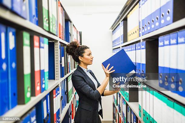 woman searching for files in paper archive - filing cabinet stock pictures, royalty-free photos & images