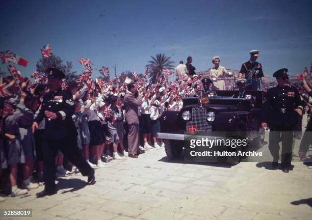 Queen Elizabeth II and Prince Philip, Duke of Edinburgh are greeted by crowds waving Union Jack flags during a visit to Malta during their...