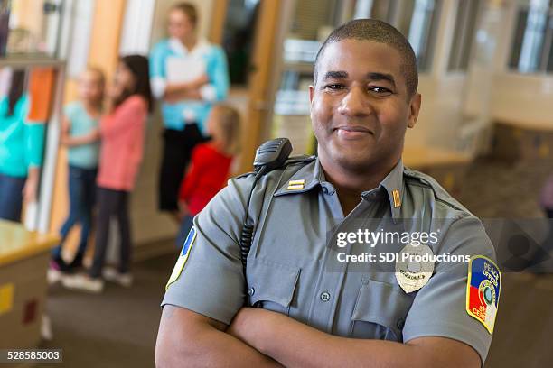 friendly school security guard working on elementary school campus - black police stock pictures, royalty-free photos & images