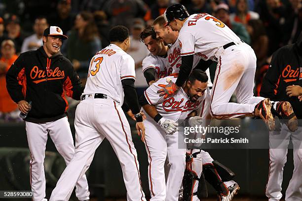 Pedro Alvarez of the Baltimore Orioles is mobbed by Ryan Flaherty and teammates after hitting a sacrifice RBI against the New York Yankees in the...