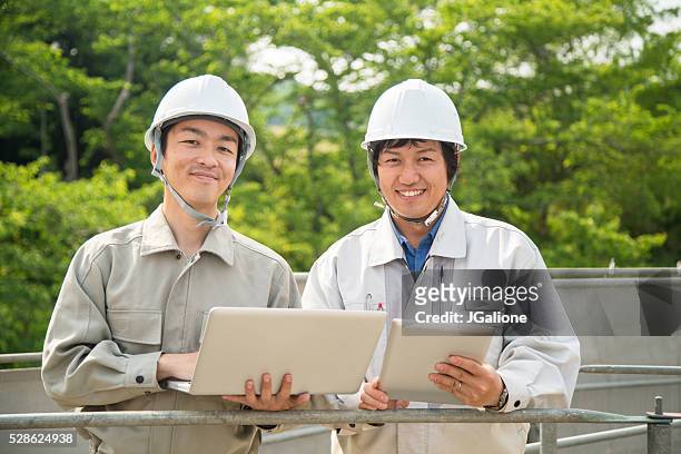 zwei bauarbeiter, die digitale geräte - business man overseeing blueprints outdoor stock-fotos und bilder