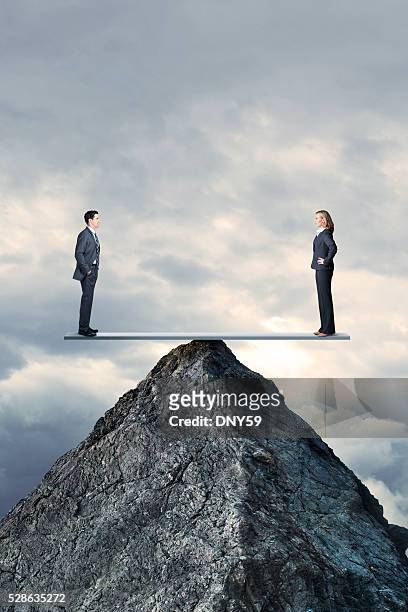 businessman and businesswoman in perfect balcance on seesaw on mountaintopbusinessman and businesswoman - justice concept stock pictures, royalty-free photos & images