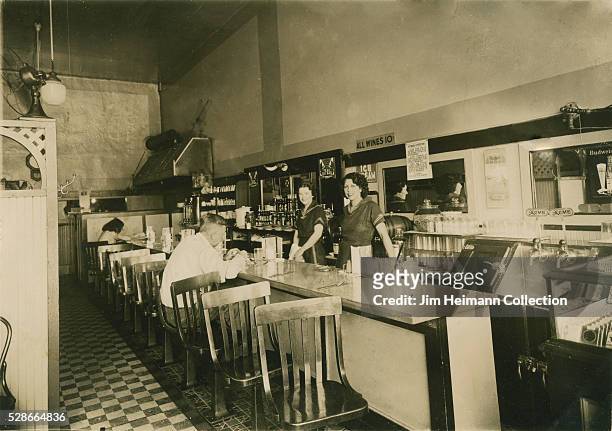 Black and white photograph featuring waitress and patron at counter in diner.