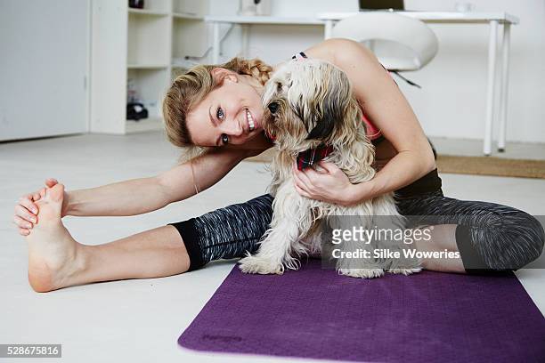 happy adult woman practicing yoga at home with her dog - yoga rug stock pictures, royalty-free photos & images