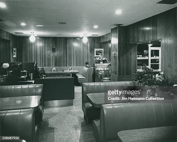 Black and white photograph of booths and plants in Copper Skillet restaurant.