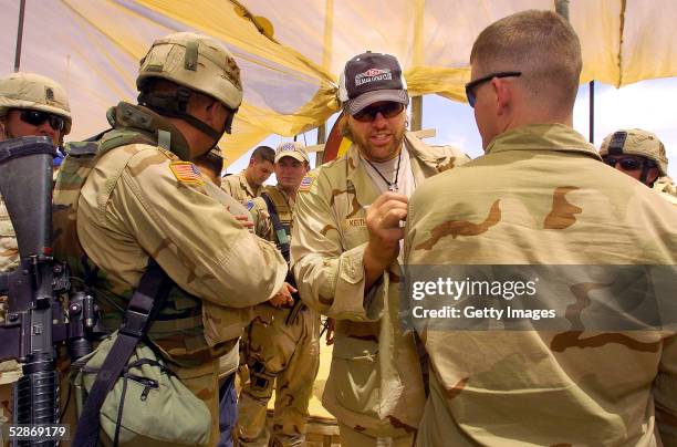 Country music star Toby Keith signs an autograph on the camouflage uniform of a U.S. Soldier May 16, 2005 after a United Service Organizations...