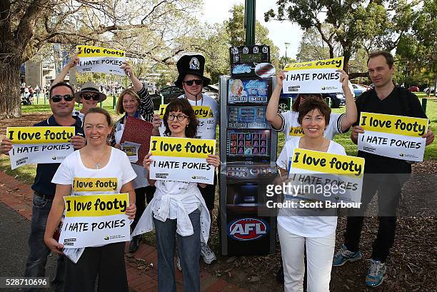 Protestors stand near a replica poker machine that shows how much Carlton and Collingwood reap from poker machines each week during a pokies protest...