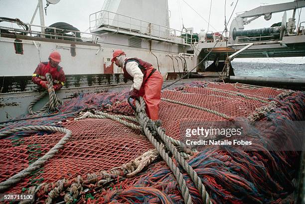 crewmen tending to trawl net on trawler deck - bering sea stock pictures, royalty-free photos & images
