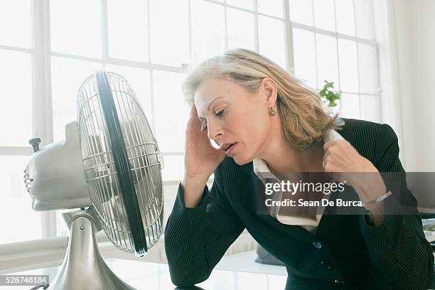 hot businesswoman sitting in front of fan - ventilateur électrique photos et images de collection