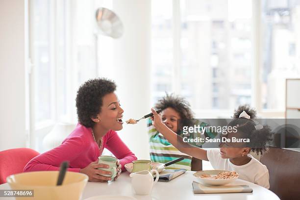 mother eating breakfast with children - eating cereal stock pictures, royalty-free photos & images