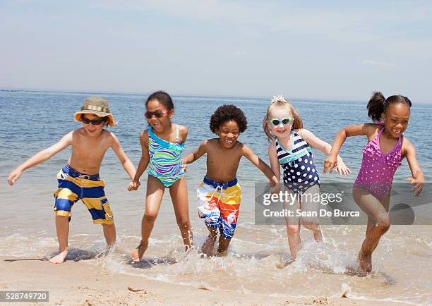 kids playing in the surf - swim suit stock pictures, royalty-free photos & images