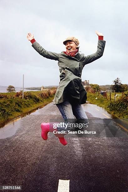 happy young woman jumping in midair - green coat stock pictures, royalty-free photos & images