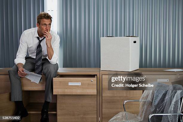 unemployed businessman packing in empty office - downsizing unemployment stock-fotos und bilder