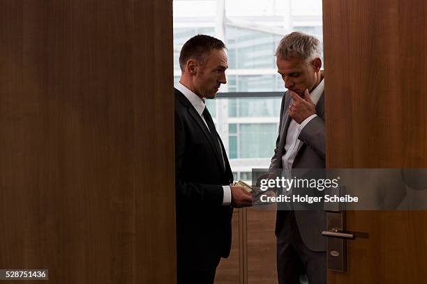 businessmen conducting bribe in conference room - corruption foto e immagini stock