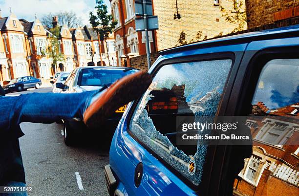person destroying car window, clapham, london, england - hooligans stockfoto's en -beelden