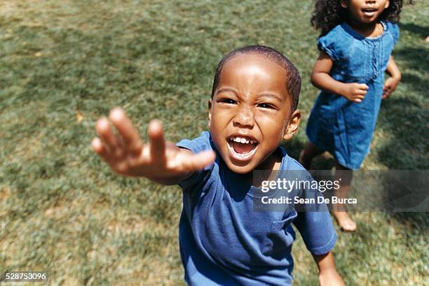 boy reaching out hand and girl in background - kin in de hand stock pictures, royalty-free photos & images