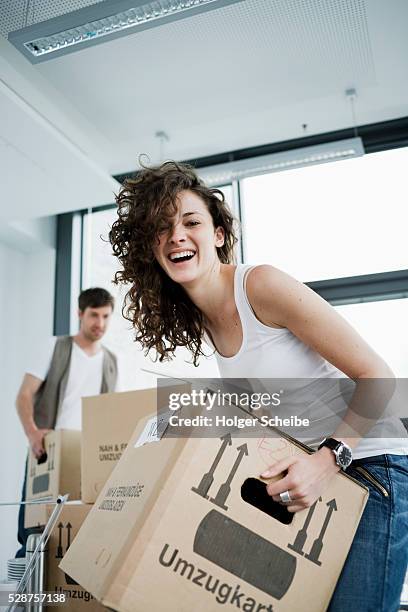 young woman lifting box in new home - box lifting technique stock-fotos und bilder