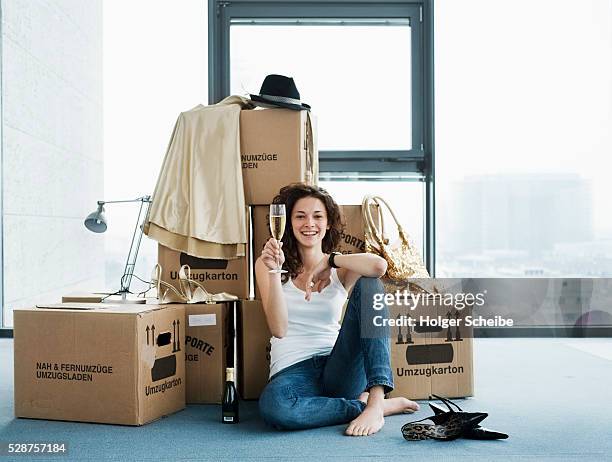 young woman sitting on floor of new home - woman holding champagne stock-fotos und bilder