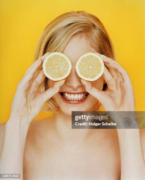 young woman holding lemons in front of her eyes - säure stock-fotos und bilder