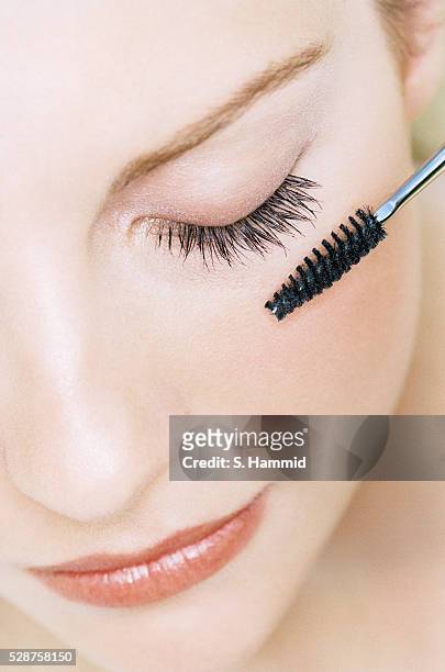 young woman applying mascara - applying makeup stockfoto's en -beelden
