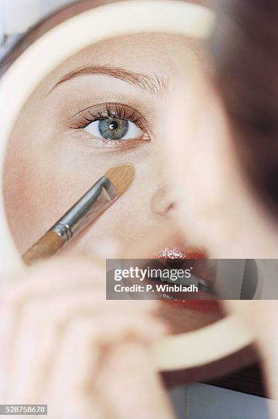 woman putting on make up - eyeshadow stock-fotos und bilder