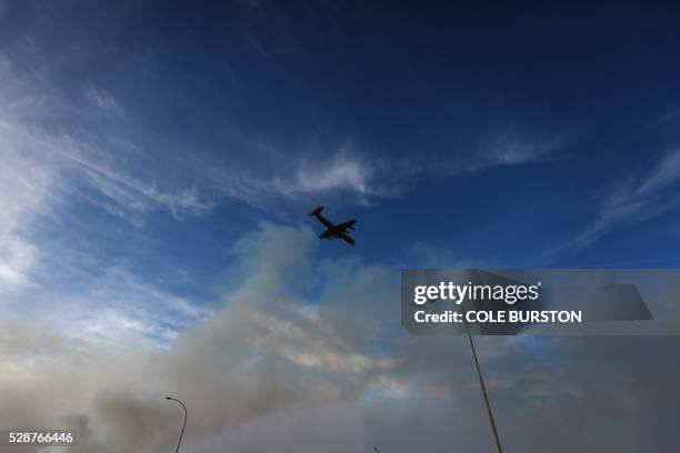 Plane flies over Highway 63 near Fort McMurray, Alberta on May 6, 2016. - Canadian police led convoys of cars through the burning ghost town of Fort...