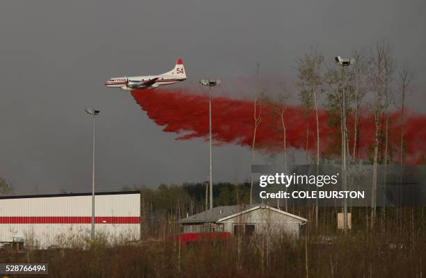 Plane drops fire retardant near a building near a road block on Highway 63 near Fort McMurray, Alberta on May 6, 2016. Canadian police led convoys of...