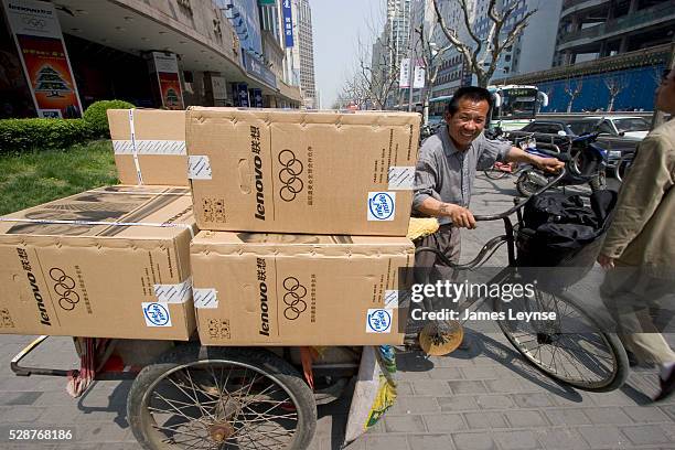 Bicycle delivery man with boxes of Lenovo computers on the street in Shanghai. Lenovo is China's largest computer manufacturer and recently completed...