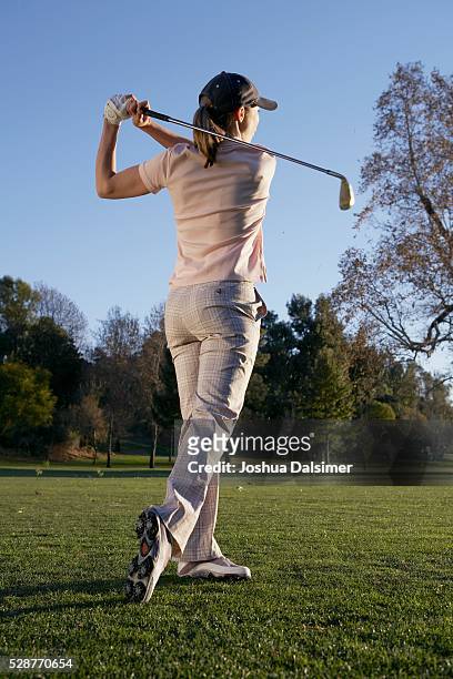 woman swinging a golf club - woman on swing foto e immagini stock