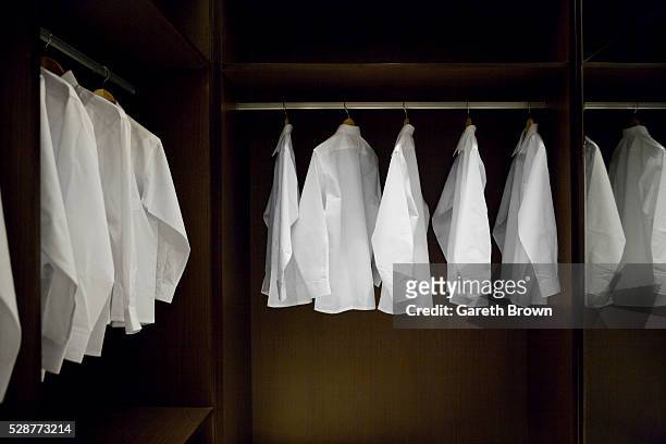 dress shirts hanging in a closet - camisa blanca fotografías e imágenes de stock