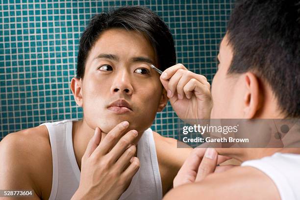 man tweezing eyebrows in mirror - man plucking eyebrows stock pictures, royalty-free photos & images