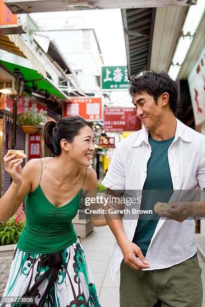young couple having snack on street - macao fotografías e imágenes de stock