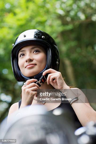 woman fastening motorcycle helmet - fastening stockfoto's en -beelden